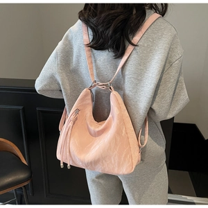 Detailed close-up of pink ruched backpack featuring long fringe tassel and metal rings