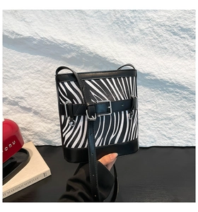 Gros plan du sac seau à imprimé zèbre avec bordure en cuir noir et boucle argentée