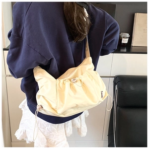 Detail of cream nylon tote bag featuring stylish pleated drawstring and side brand label