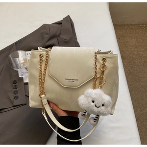 Detail view of cream chain shoulder bag with leather texture and plush cloud charm