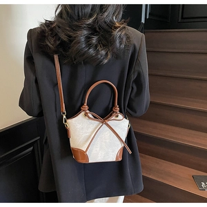 Detail of vintage bucket bag with contrast stitching and leather bow decoration