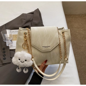 Detail of cream shoulder bag with marble texture, gold chain and cloud plush charm