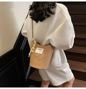 Détail de la texture cuir de lychee sur le sac seau kaki avec foulard en soie