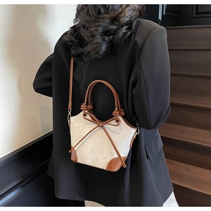 Detail showing vintage cream bucket bag with brown bow and elegant contrast texture