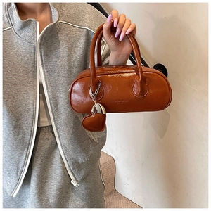 Détail du sac baguette marron brillant avec pendentif cœur et logo Fashion Bags
