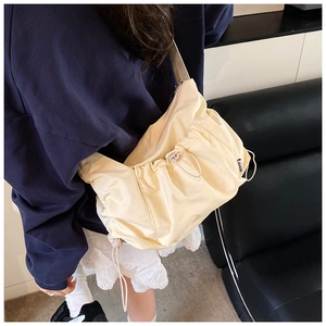 Detail view of a pleated cream nylon tote bag with a drawstring design and side label