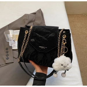Detail of black pleated leather bag with gold chain strap and plush cloud charm