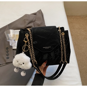 Detail of black pleated PU leather shoulder bag with golden chain and plush cloud charm