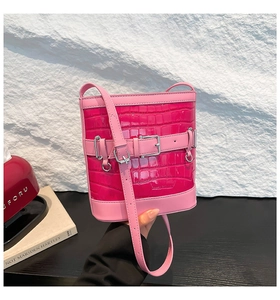 Détail du sac seau rose vif avec texture crocodile gaufrée et boucle argentée chic