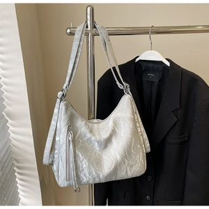 Detail of silver pleated hobo bag with fringe pendant and metallic zipper decoration