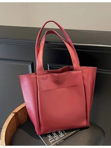 Minimalist burgundy tote bag with front pocket and double handles on a wooden chair