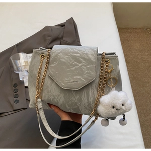 Detail of grey PU leather bag featuring natural pleated texture and a plush cloud charm