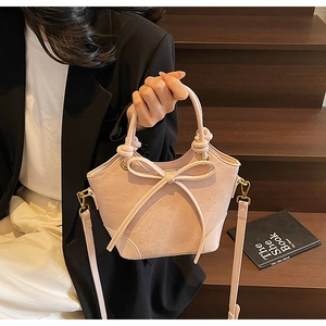 Close-up of light pink bucket bag with a bow detail and textured matte finish texture