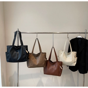 Detail showing four leather tote bags in black, brown, tan, and beige on metal hooks