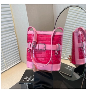 Détail du sac seau texture crocodile fuchsia avec boucle rose et finitions métalliques