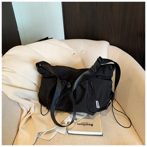 Detail of black nylon crossbody bag with drawstring design and fashion label on a sofa