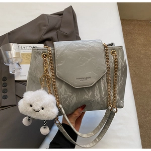 Detail of grey wrinkled leather texture with gold chain strap and plush cloud charm