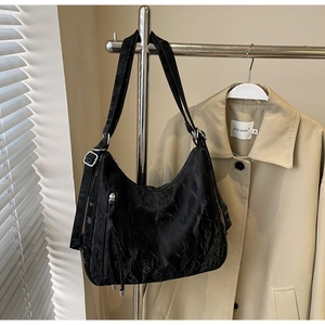 Detail of black pleated tote bag with silver buckle and adjustable wide strap