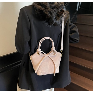 Detail of pink faux leather bucket bag with bow accent and gold metal hardware clasp