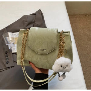 Detail of light green pleated leather bag with gold chains and plush cloud accessory
