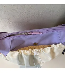 Detail view of smooth metal zipper and drawstring pocket on purple canvas shoulder bag