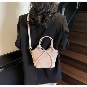 Rear view of a model wearing a pink trapezoidal handbag with a delicate bow accent