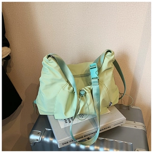 Detail of mint green nylon tote with drawstring design and plastic buckle on magazines