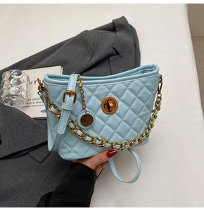 Detail of light blue quilted tote bag with gold chain strap and metal charm