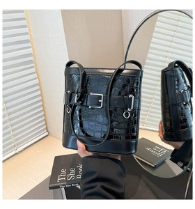 Détail du sac seau noir motif crocodile avec boucle métallique et bandoulière en cuir
