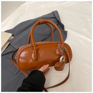 Vue détaillée du sac polochon en cuir marron avec breloque cœur et bandoulière