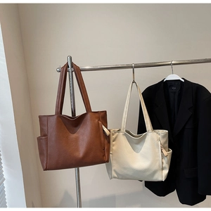 Detail of minimalist tote bags in brown and beige with side pockets and V-cut design
