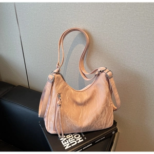 Detail of light pink textured leather tote bag featuring silver hardware and tassel zippers