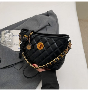 Detail of black quilted leather tote with gold twist lock and chain strap on grey blazer