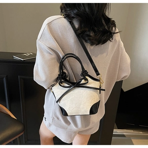 Detailed close-up of marble pattern bucket bag with black bow and gold hardware