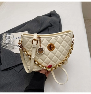 Detailed shot of cream quilted texture bag with vintage gold turn-lock and chain strap