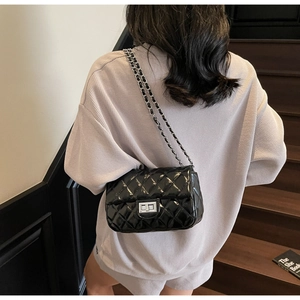 Quilted chain shoulder bag in black patent leather shown from back on model