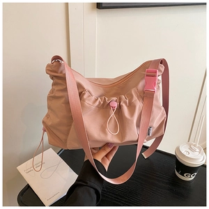 Detail view of pink nylon tote bag featuring drawstring pleats and adjustable strap
