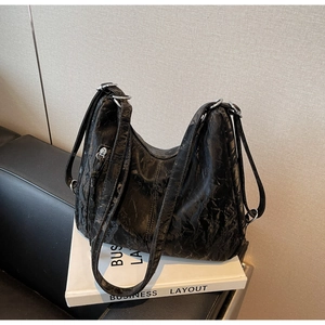 Close-up of black pleated faux leather shoulder bag with metallic silver ring hardware detail