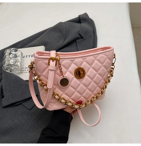 Detailed view of pink quilted handbag with gold hardware clasp and metal chain strap