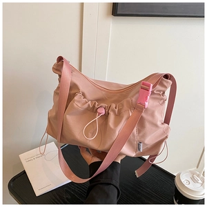 Close-up of pink nylon tote bag showing pleated drawstring pocket and plastic buckle