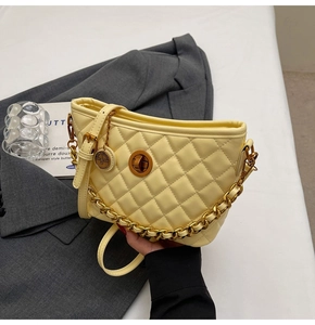 Detail of yellow quilted crossbody bag with gold chain strap and turn-lock closure