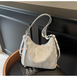 Close-up of silver-gray pleated hobo bag with zip pocket on a minimalist wooden stool