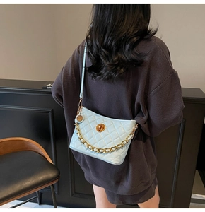 Detail of light blue quilted crossbody bag with gold chain strap and metal turn-lock