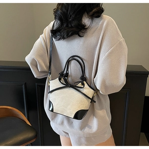 Close-up of beige canvas bucket bag with black leather bow detail worn by model