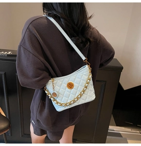 Close-up of light blue quilted crossbody bag with gold chain strap and turn-lock