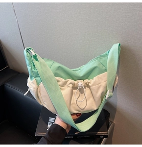 Detail of mint green and white nylon dumpling bag with adjustable strap and drawstring
