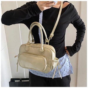 Beige faux leather Boston bag with gold hardware shown on a model for scale and fit