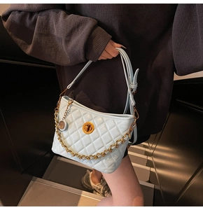 Detail of light blue quilted tote bag featuring gold chain and turn-lock closure