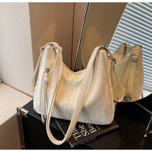 Detail of soft cream leather shoulder bag with tassel zipper and silver metal buckle