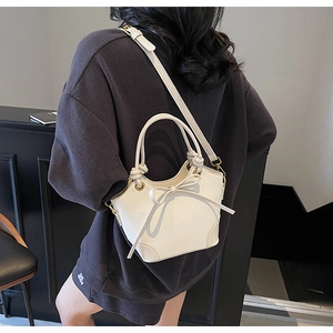 Back view of model carrying a white bucket bag with elegant bow and slim strap